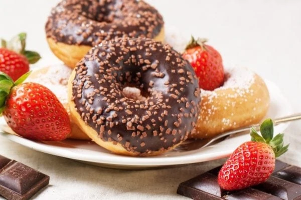 chocolate glazed donuts with sprinkles and strawberries on a plate