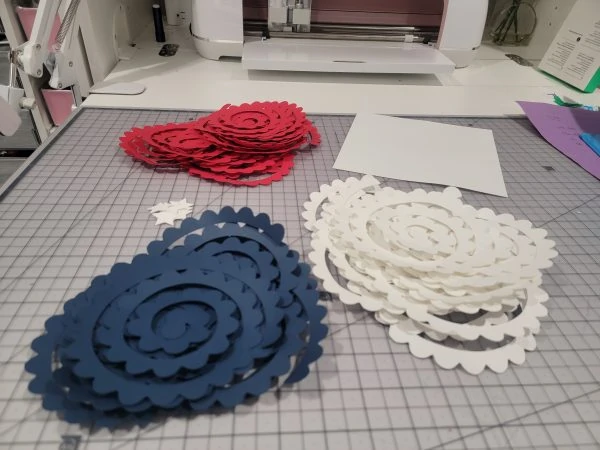 all the materials to make an american flag paper flower shadow box cut out and on a table. 