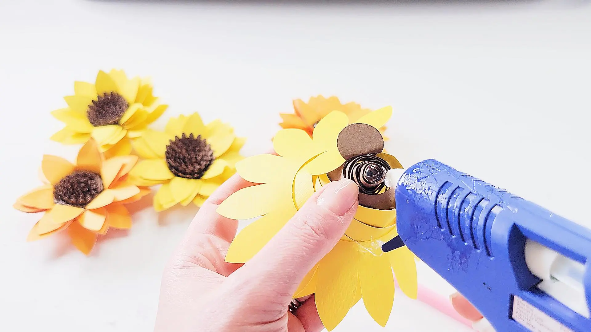 gluing the center of a sunflower paper flower with hot glue