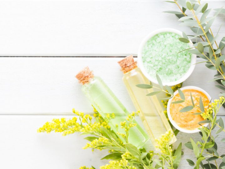 natural skincare products sitting on a white surface surrounded by herbs